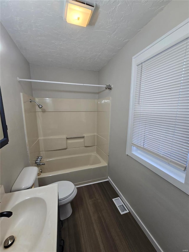 full bathroom with hardwood / wood-style floors,  shower combination, sink, toilet, and a textured ceiling