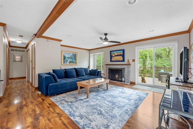 living room with hardwood / wood-style flooring, ceiling fan, a fireplace, and crown molding