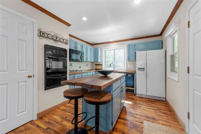 kitchen with wood counters, a breakfast bar, blue cabinets, black appliances, and a kitchen island