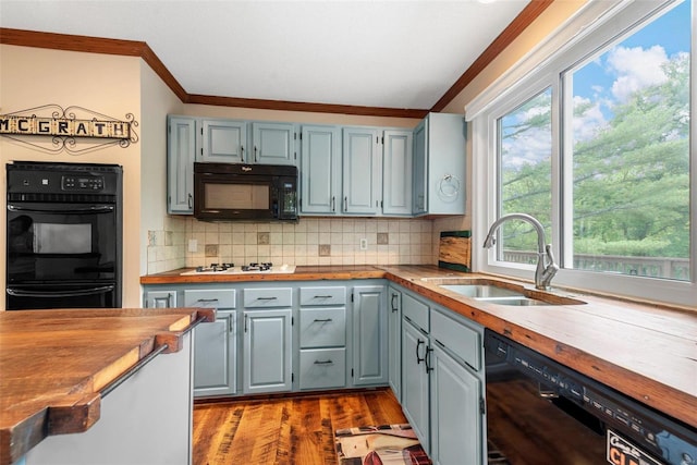 kitchen with black appliances, crown molding, sink, decorative backsplash, and butcher block counters