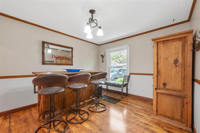 bar featuring decorative light fixtures, light hardwood / wood-style floors, and crown molding