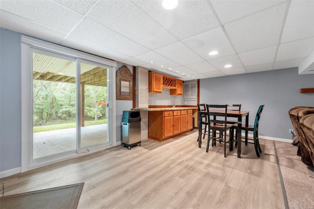 kitchen with a paneled ceiling, sink, and light hardwood / wood-style flooring