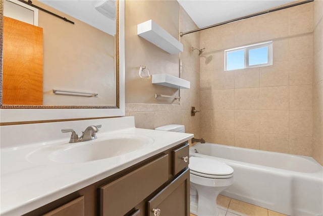 full bathroom with vanity, tile walls, tile patterned flooring, toilet, and tiled shower / bath