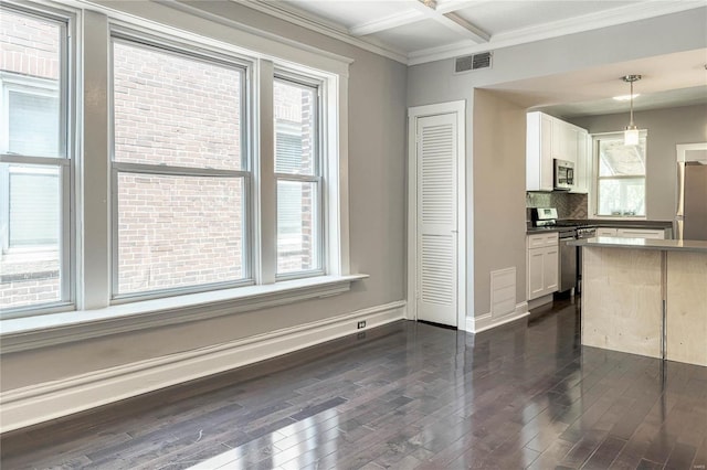 interior space featuring tasteful backsplash, white cabinets, stainless steel appliances, and decorative light fixtures