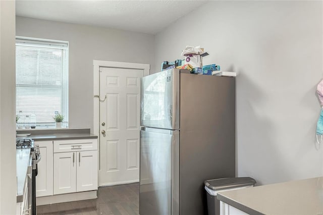 kitchen with dark hardwood / wood-style flooring, white cabinets, stainless steel appliances, and a textured ceiling