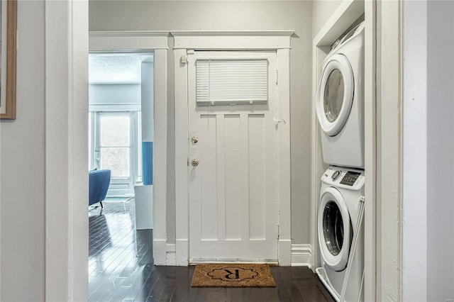 laundry area with dark hardwood / wood-style floors, stacked washing maching and dryer, and a textured ceiling