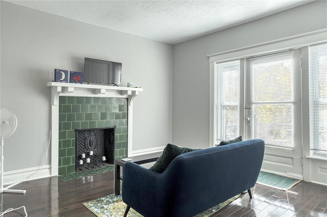 living room featuring dark hardwood / wood-style flooring, a textured ceiling, and a tiled fireplace