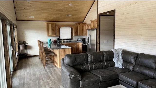 living room with hardwood / wood-style floors, wooden ceiling, sink, and vaulted ceiling