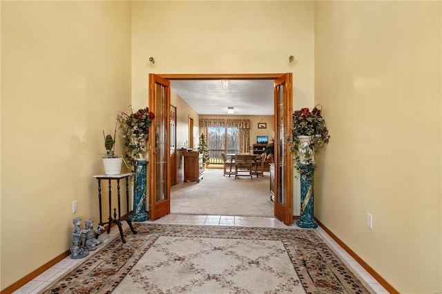 hallway with french doors, light tile patterned flooring, and a textured ceiling