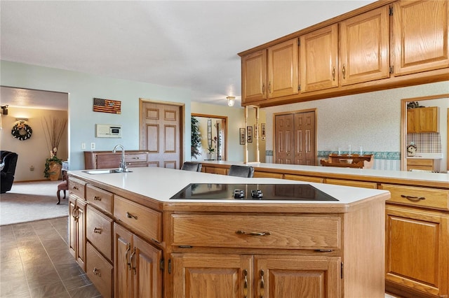 kitchen featuring black electric cooktop, sink, and a center island with sink