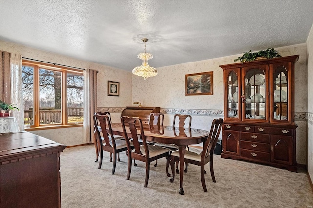 dining room featuring a textured ceiling, light colored carpet, and an inviting chandelier