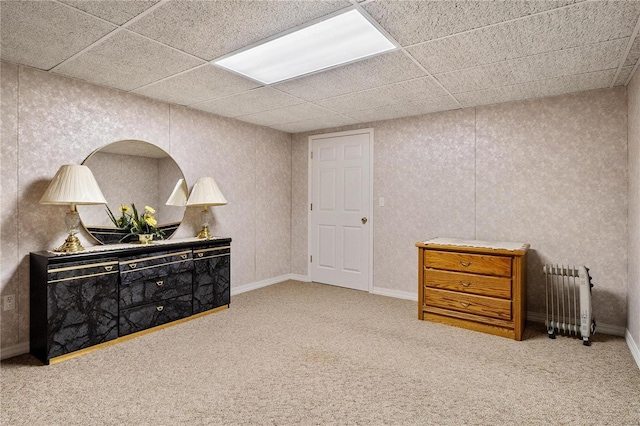 interior space with carpet flooring, radiator, and a paneled ceiling