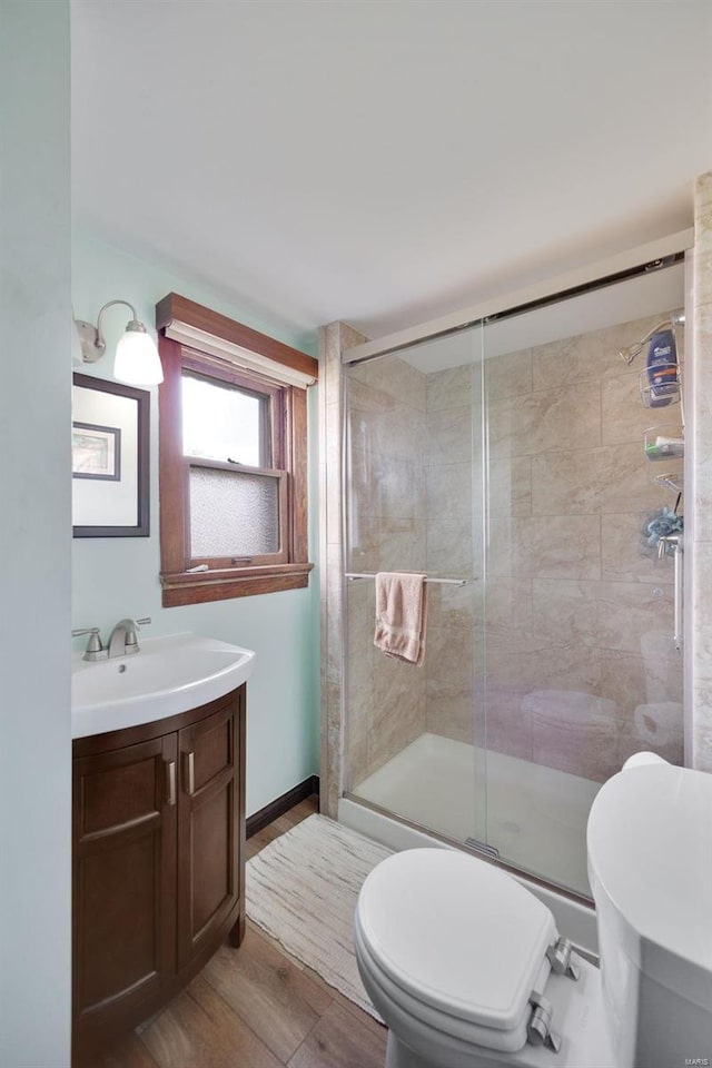 bathroom with hardwood / wood-style flooring, vanity, toilet, and a shower with door