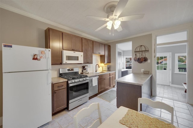 kitchen with sink, crown molding, light tile patterned floors, ceiling fan, and stainless steel appliances