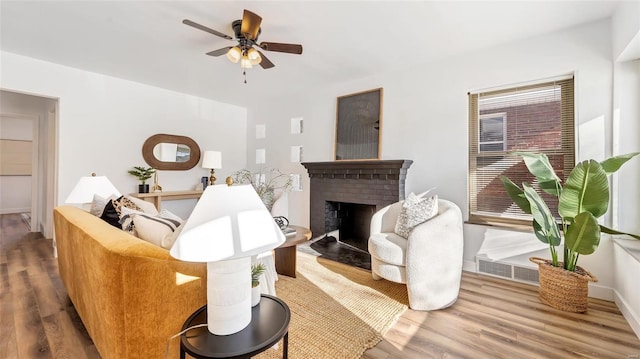 living room featuring ceiling fan, wood-type flooring, and a fireplace