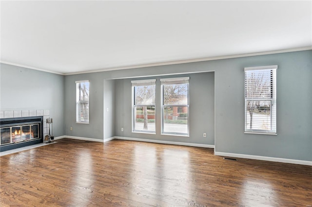 unfurnished living room featuring dark hardwood / wood-style floors, ornamental molding, and a tile fireplace