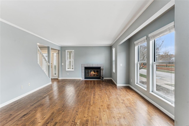 unfurnished living room with a tiled fireplace, hardwood / wood-style flooring, and ornamental molding