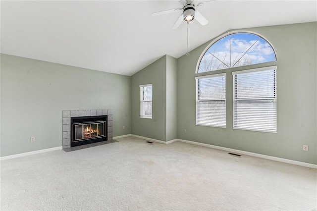 unfurnished living room with ceiling fan, light colored carpet, a tile fireplace, and vaulted ceiling