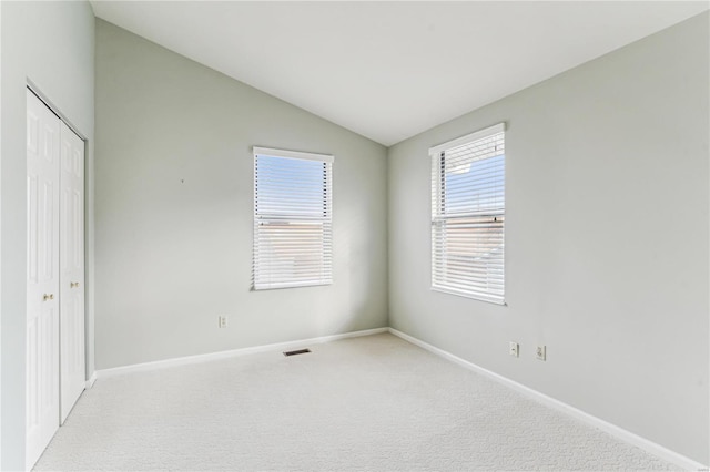 unfurnished bedroom featuring a closet, light colored carpet, and vaulted ceiling