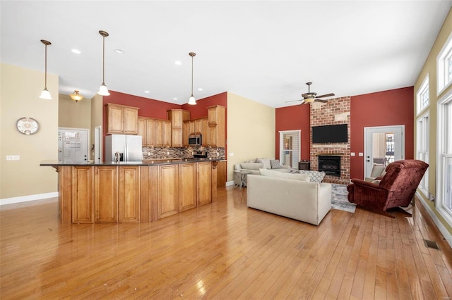 kitchen with light wood-style flooring, stainless steel appliances, decorative backsplash, dark countertops, and open floor plan