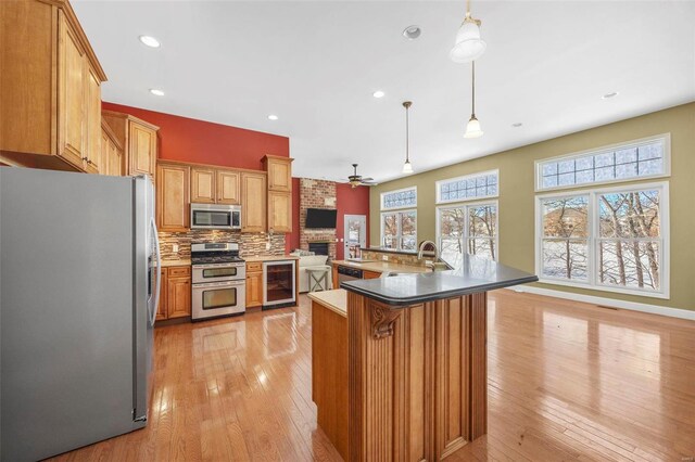 kitchen with ceiling fan, wine cooler, appliances with stainless steel finishes, light wood-style floors, and a sink