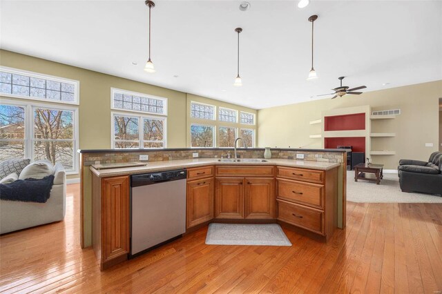 kitchen with brown cabinetry, a fireplace, a sink, dishwasher, and open floor plan