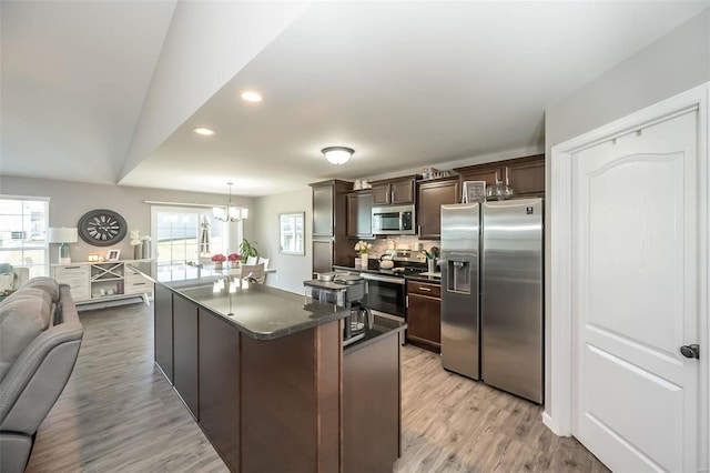 kitchen featuring stainless steel appliances, a kitchen island, dark brown cabinets, and light hardwood / wood-style flooring