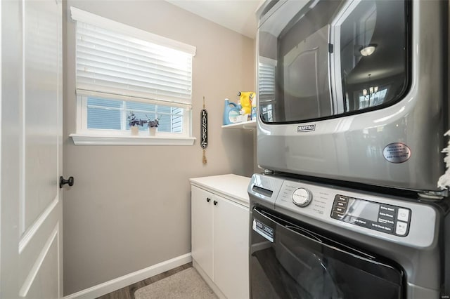 washroom with stacked washer and dryer, cabinets, and light hardwood / wood-style floors