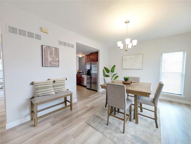 dining area featuring light hardwood / wood-style flooring, a chandelier, and sink