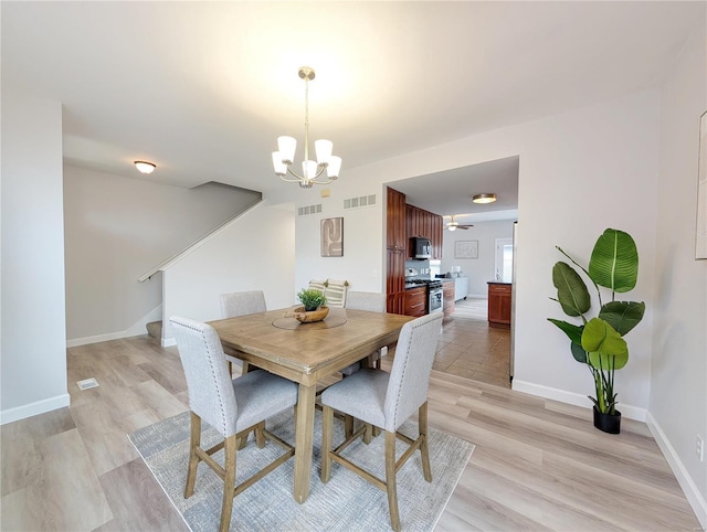 dining space featuring light hardwood / wood-style flooring and ceiling fan with notable chandelier