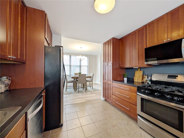 kitchen with light tile patterned floors, decorative light fixtures, a notable chandelier, and appliances with stainless steel finishes