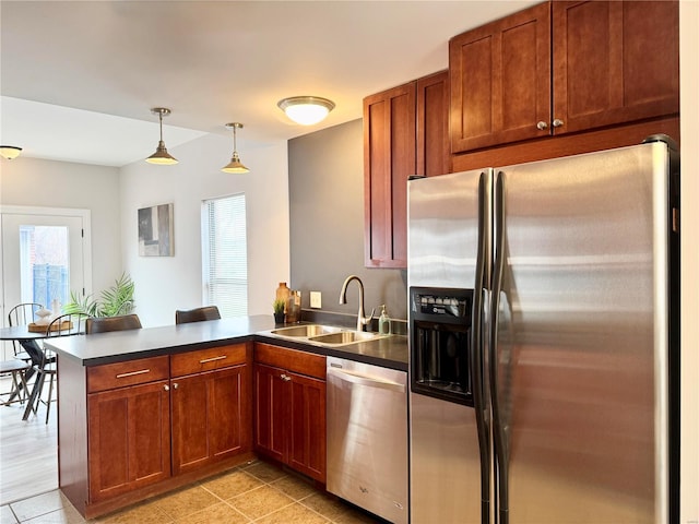 kitchen featuring kitchen peninsula, appliances with stainless steel finishes, sink, light tile patterned floors, and decorative light fixtures