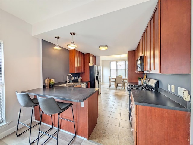 kitchen featuring kitchen peninsula, appliances with stainless steel finishes, a breakfast bar, light tile patterned floors, and decorative light fixtures