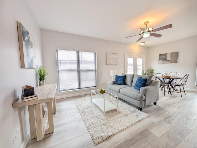 living room featuring ceiling fan, a healthy amount of sunlight, light wood-type flooring, and french doors