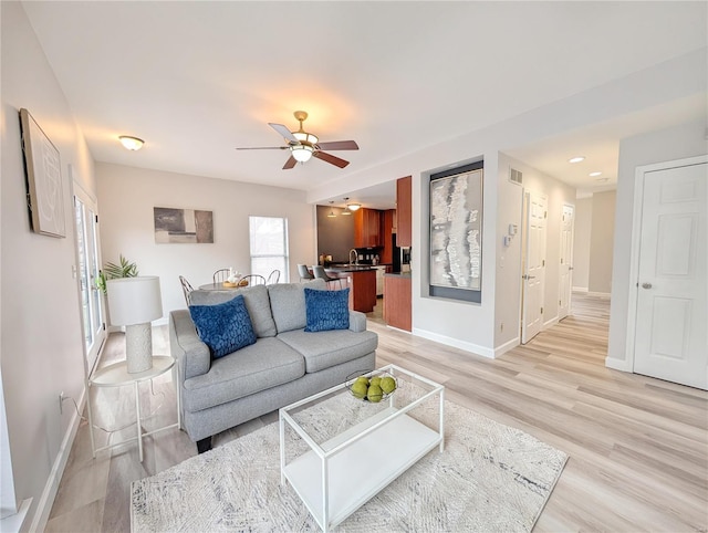 living room featuring a wealth of natural light, ceiling fan, and light hardwood / wood-style floors