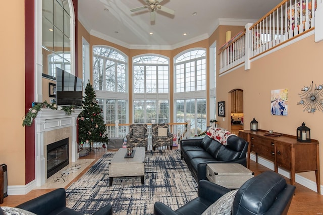 living room featuring plenty of natural light, ceiling fan, crown molding, and a fireplace