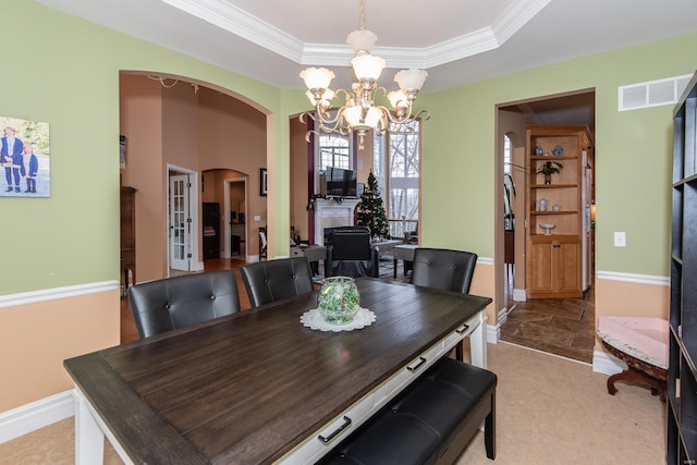 dining room featuring a chandelier, crown molding, light carpet, and a tray ceiling