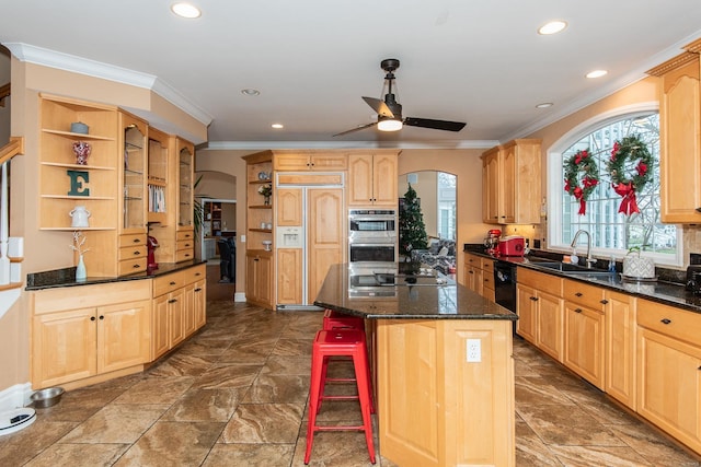 kitchen with appliances with stainless steel finishes, dark stone counters, sink, a kitchen island, and a breakfast bar area