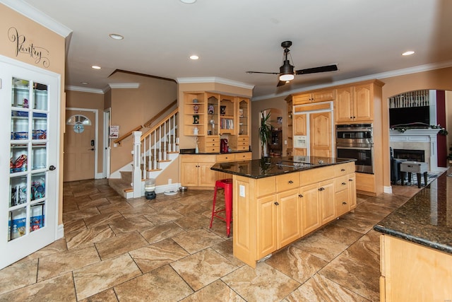 kitchen with ceiling fan, stainless steel double oven, paneled refrigerator, dark stone countertops, and a kitchen island