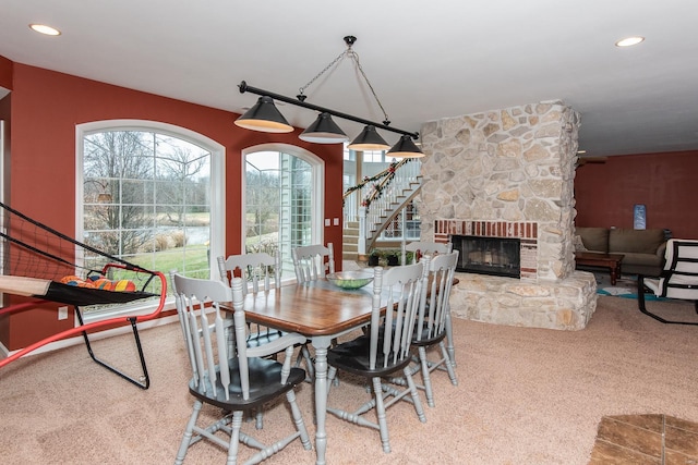 dining area featuring carpet and a stone fireplace