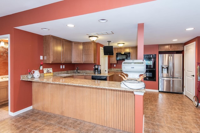 kitchen featuring kitchen peninsula, sink, light stone counters, and black appliances