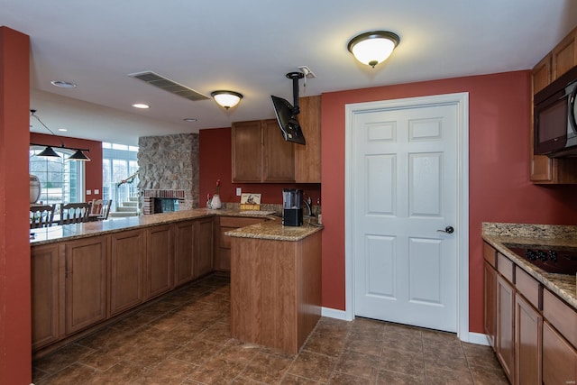 kitchen with pendant lighting, a stone fireplace, light stone countertops, stovetop, and kitchen peninsula