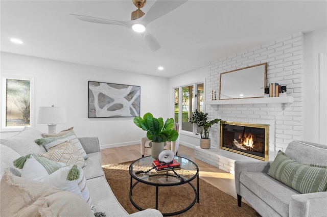 living room with hardwood / wood-style floors, a brick fireplace, and ceiling fan