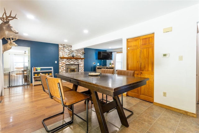 dining area with wood-type flooring and a brick fireplace