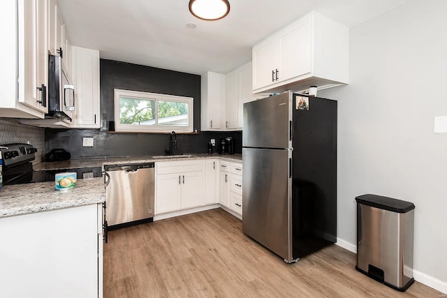 kitchen featuring sink, stainless steel appliances, light stone counters, light hardwood / wood-style floors, and white cabinets