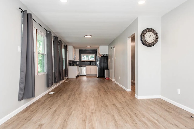 unfurnished living room featuring sink and light hardwood / wood-style floors