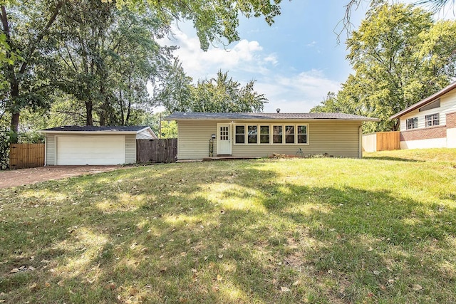 rear view of house with a yard, a garage, and an outdoor structure