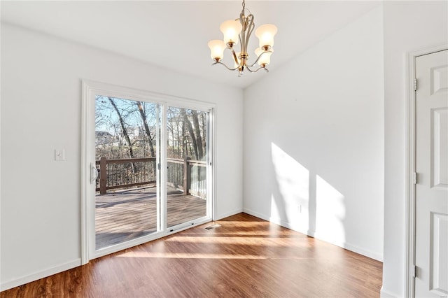 unfurnished dining area featuring hardwood / wood-style floors, lofted ceiling, and a notable chandelier