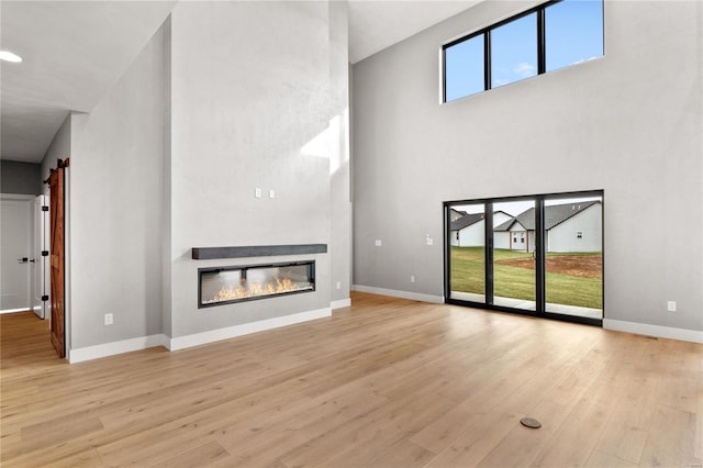 unfurnished living room featuring plenty of natural light, a high ceiling, and light wood-type flooring