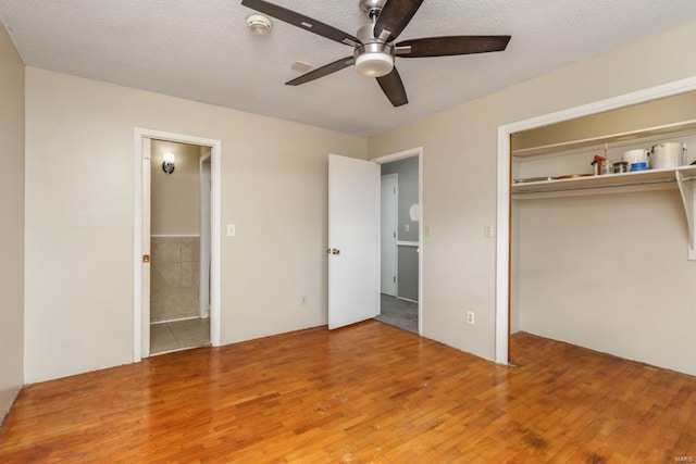 unfurnished bedroom featuring ceiling fan, wood-type flooring, a textured ceiling, and a closet